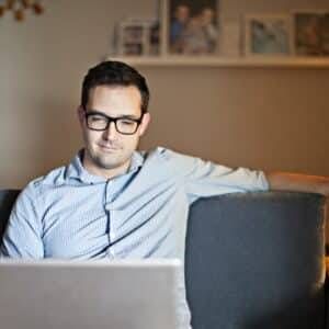 A man sitting on a couch using a laptop.