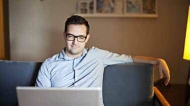 A man sitting on a couch using a laptop.