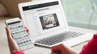A woman is using a laptop and cell phone to look at a real estate website.