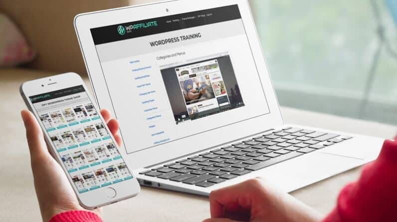 A woman is using a laptop and cell phone to look at a real estate website.