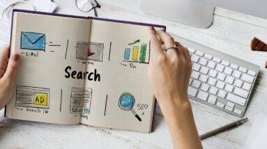 A hand holding a book with the word search written on it.