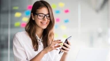 A woman in glasses is using a cell phone.