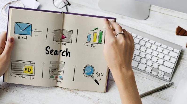 A hand holding a book with the word search written on it.