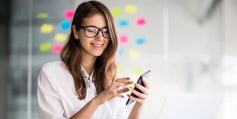 A woman in glasses is using a cell phone.