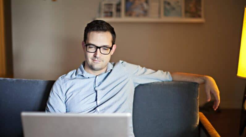 A man sitting on a couch using a laptop.