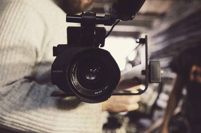 A man holding a video camera in a warehouse.