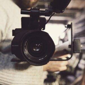 A man holding a video camera in a warehouse.