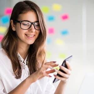 A woman in glasses is using a cell phone.